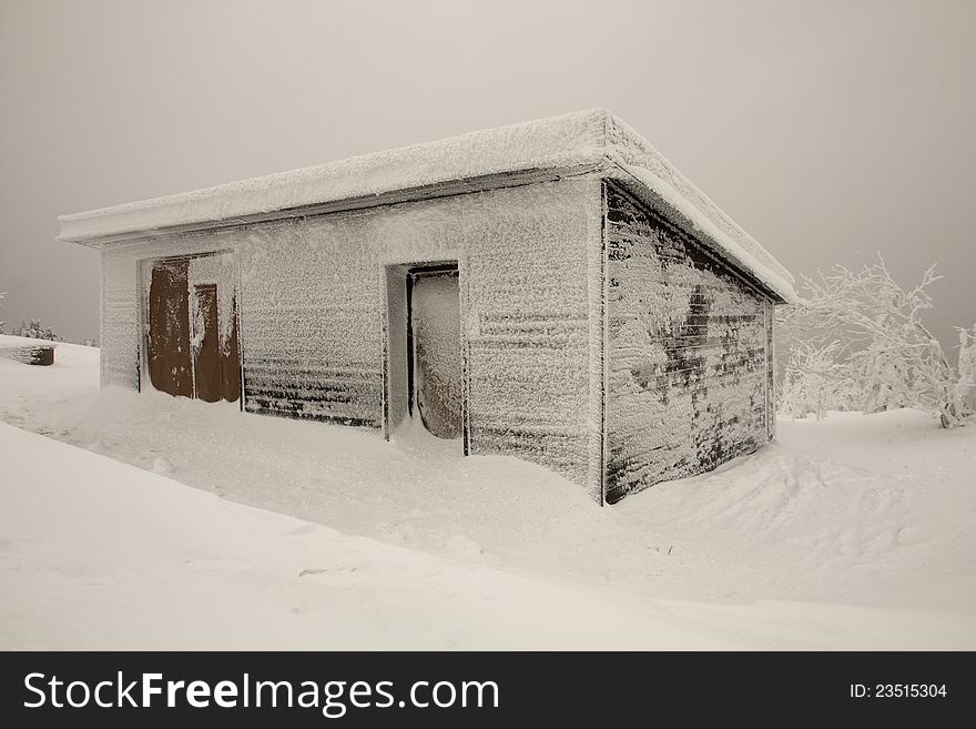 Frozen ski hut, wooden hut in the mountains, a wooden shed in a winter landscape, winter des overcast with a wooden shed, cold in the Czech mountains. Frozen ski hut, wooden hut in the mountains, a wooden shed in a winter landscape, winter des overcast with a wooden shed, cold in the Czech mountains