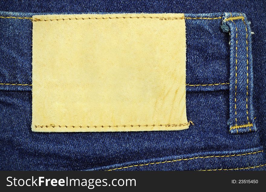 Blank leather jeans label sewed on a blue jeans, used as background for your text.