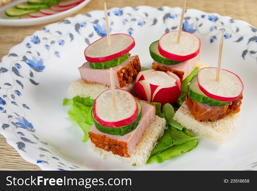 Canape with radishes, ham, cucumber on plate