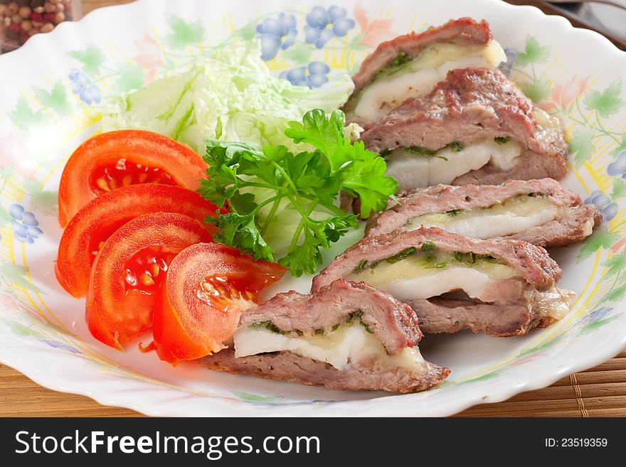 Meat filled with bacon and cheese, tomatoes, parsley on plate