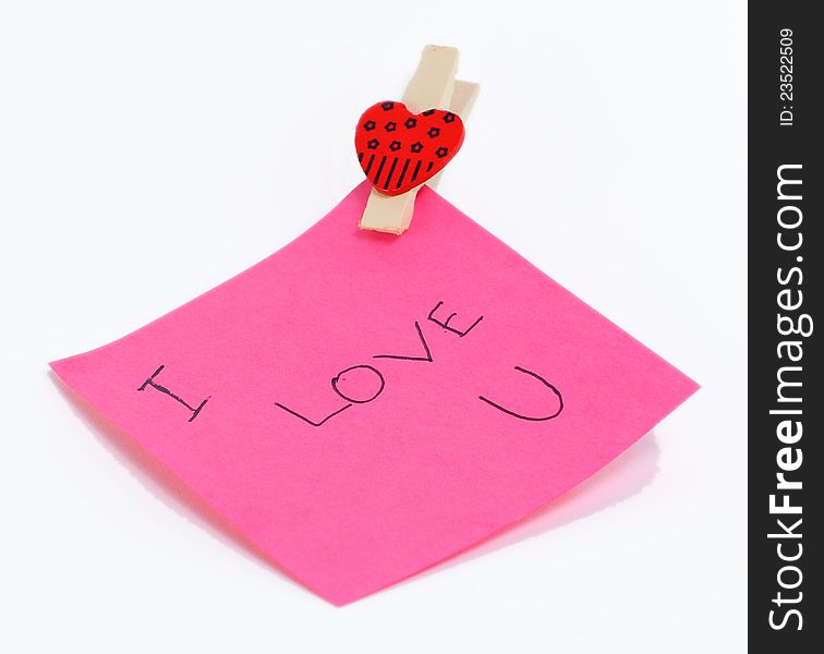 I love you note with heart clip on a piece of pink paper. I love you note with heart clip on a piece of pink paper