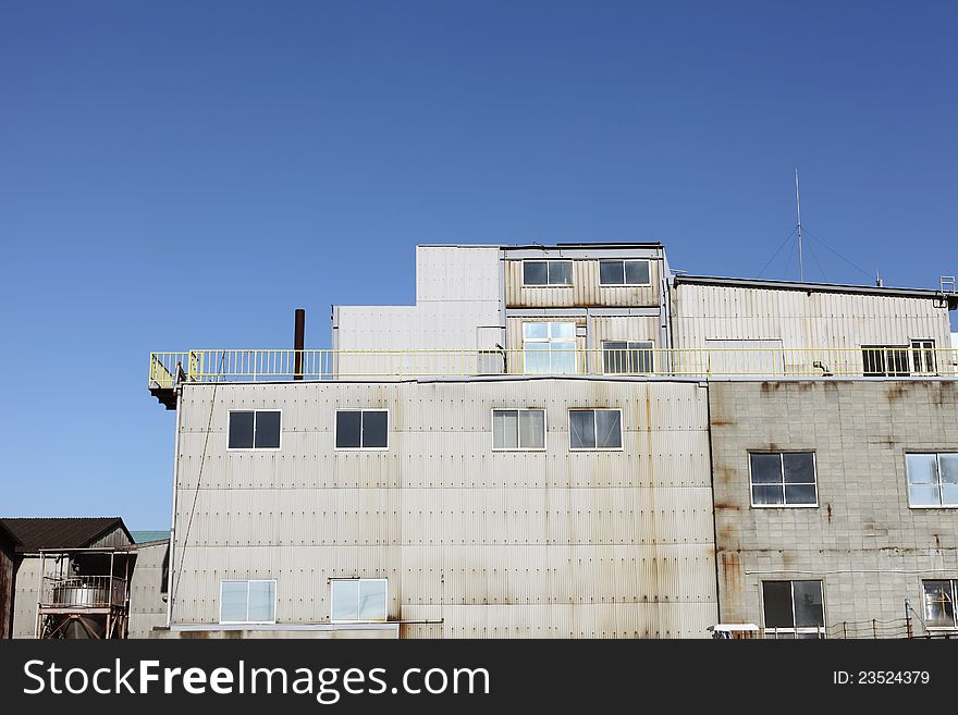 View of grunge factory against blue sky