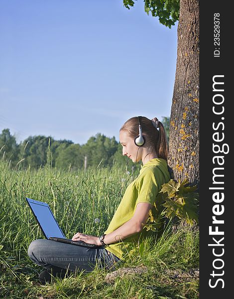 Teenage girl with headphones and computer at the country side. Teenage girl with headphones and computer at the country side