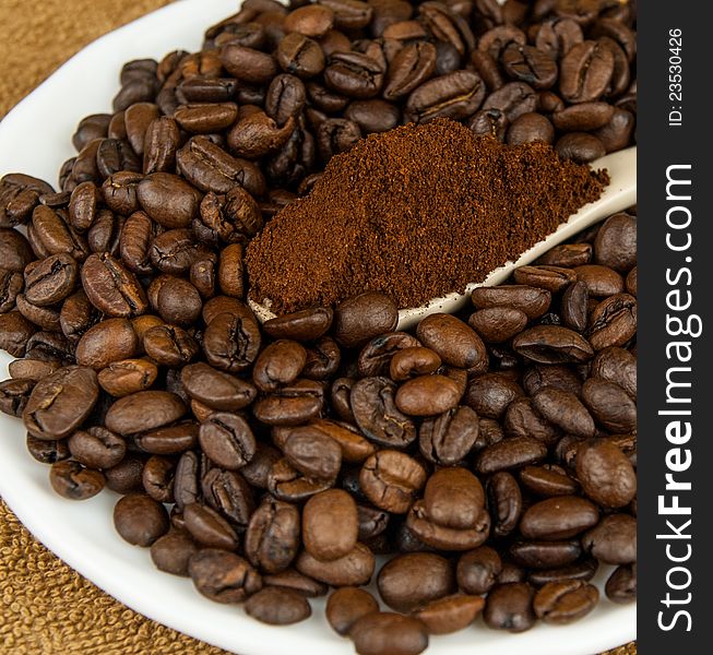 Coffee beans and ground coffee in a spoon on the plate. Coffee beans and ground coffee in a spoon on the plate