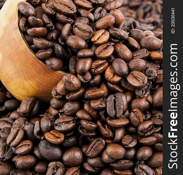 Coffee beans in a wooden spoon and as a background.