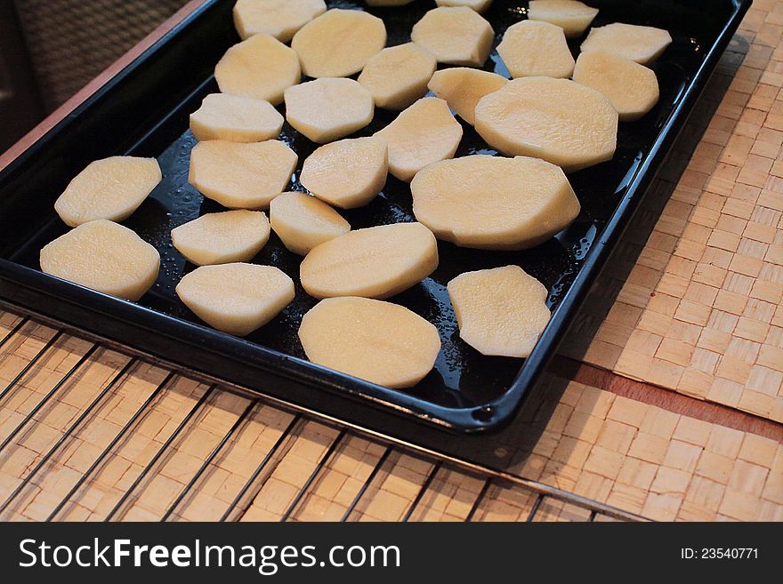 Raw potato slices on an metallic pan before baking in oven. Raw potato slices on an metallic pan before baking in oven.