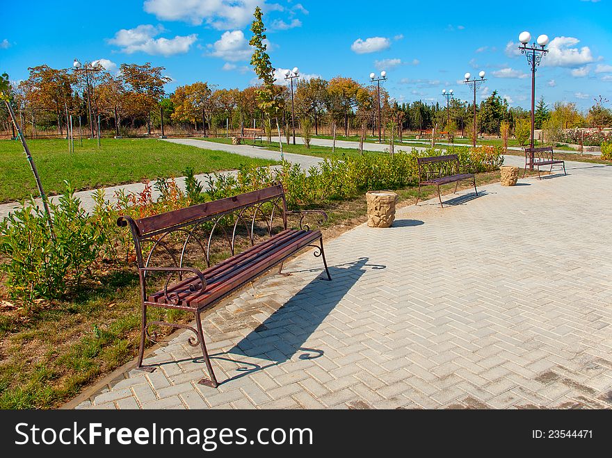 Autumn city park with benches, lawns, walkways, and lights