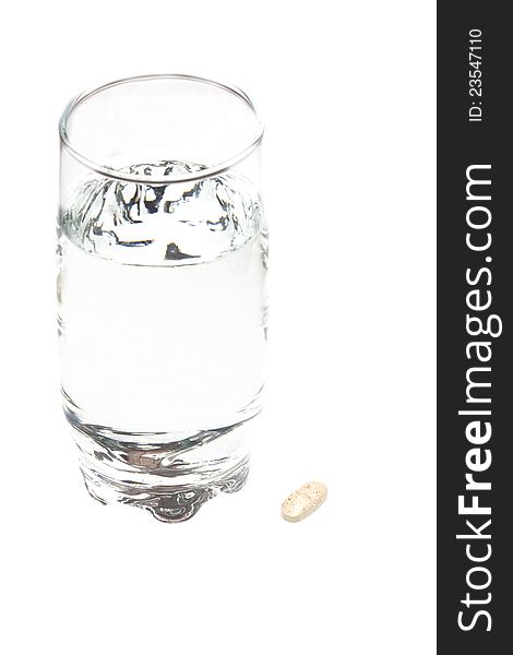 A glass of water and a tablet on a white background. A glass of water and a tablet on a white background.