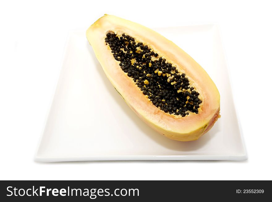 Half of the papaya fruit on a plate on a white background