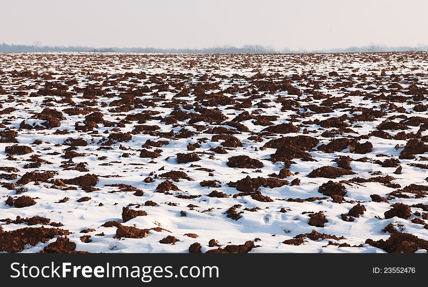Image of an agricultural field partially covered by snow in winter. Image of an agricultural field partially covered by snow in winter.