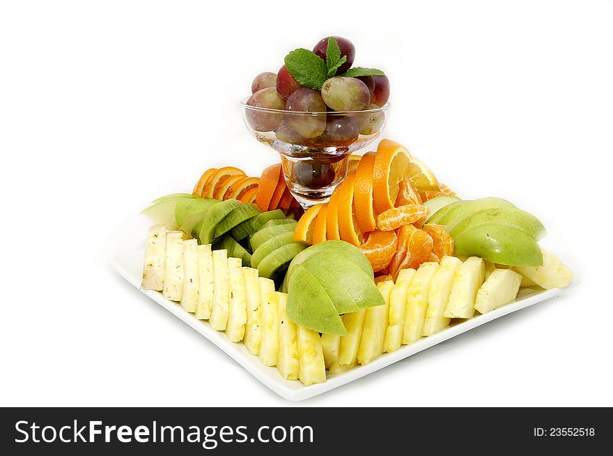 A plate of beautifully sliced fruit on white background. A plate of beautifully sliced fruit on white background