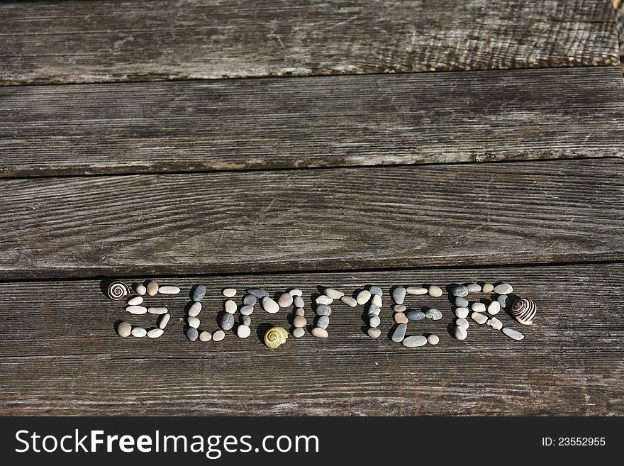 Summer word made of little stones on the beach bench