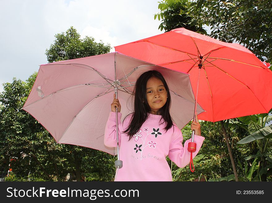 A little girl under umbrellas.