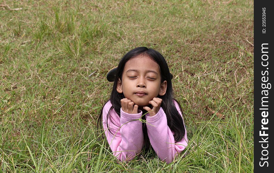 Little girl lying on green field of grass. Little girl lying on green field of grass.