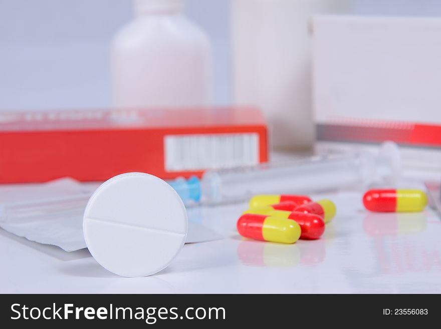 Different pills, packs and syringe on table, selective focus