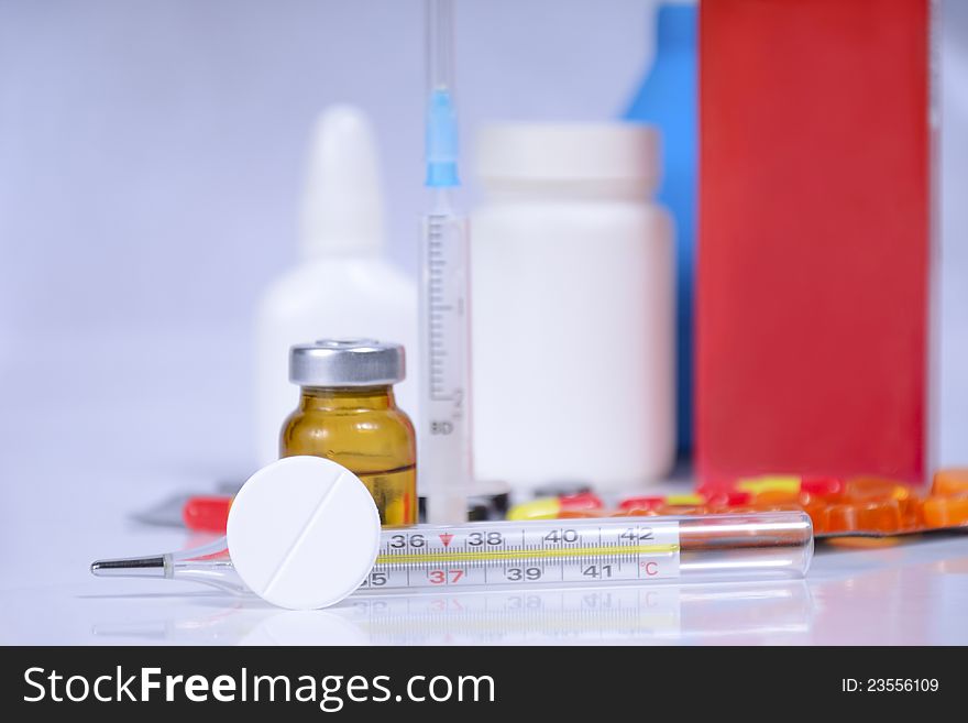 Different pills, thermometr, packs and syringe on table, selective focus. Different pills, thermometr, packs and syringe on table, selective focus