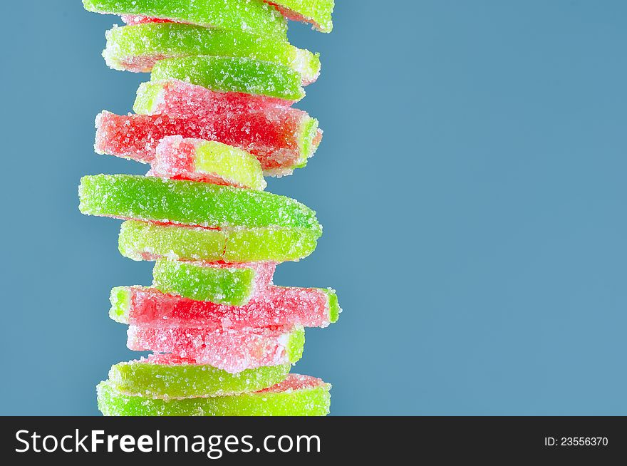 A stack of fruit jelly watermelon candies on a blue background with copy space. A stack of fruit jelly watermelon candies on a blue background with copy space