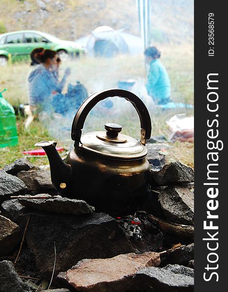 Kettle on the fire on the background of a picnic with tents. Kettle on the fire on the background of a picnic with tents