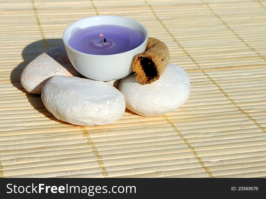 Lighted purple candle on bamboo place mat