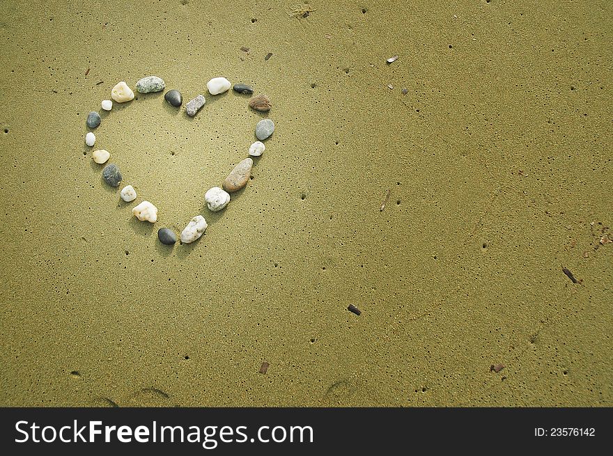 Heart made of small stones on sand