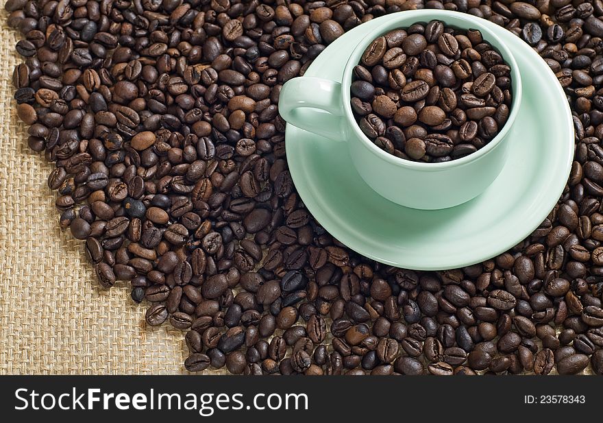 Coffee bean in the coffee cup shot with coffee bean and burlap background. Coffee bean in the coffee cup shot with coffee bean and burlap background