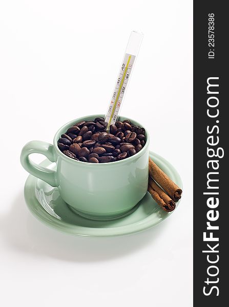Coffee bean in the coffee cup served with cinnamon and termometer, shot with coffee bean background. Coffee bean in the coffee cup served with cinnamon and termometer, shot with coffee bean background