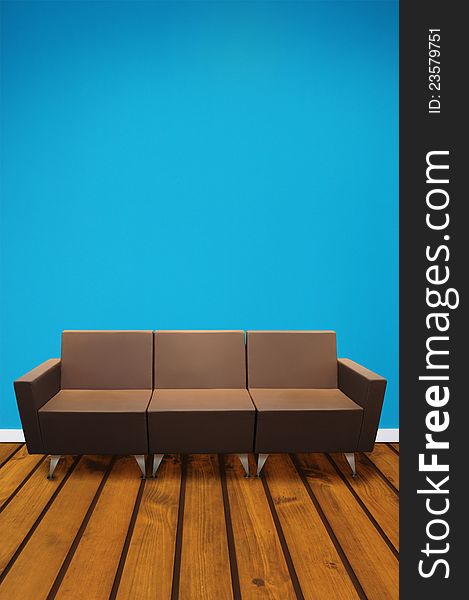 Brown couch on wooden floor against blue background. Brown couch on wooden floor against blue background.