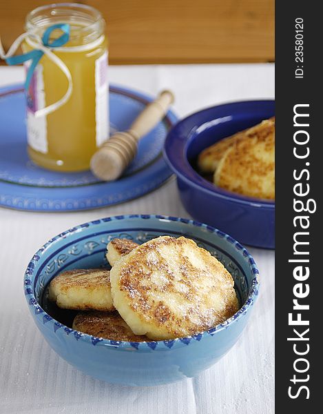 Fresh tasty cheese pancakes in blue bowl and a jar with honey