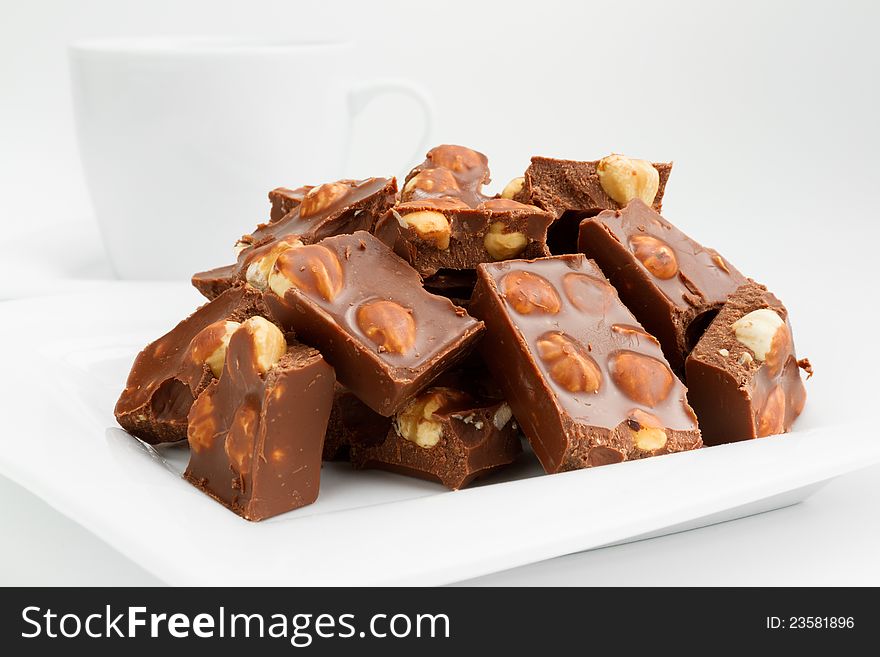 Broken chocolate pieces with nuts on white plate