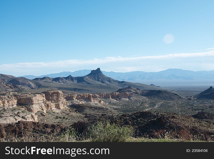 A typical Arizona landscape with desert, weathered rocky buttes and distant mountain peaks. A typical Arizona landscape with desert, weathered rocky buttes and distant mountain peaks.