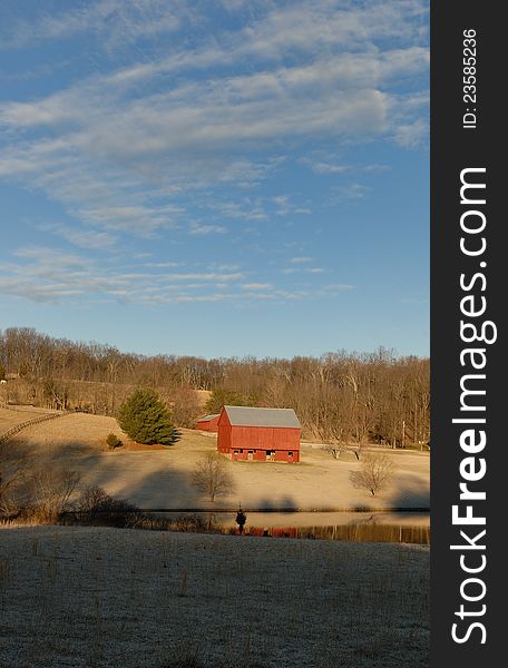 Red barn in morning light with pond in foreground