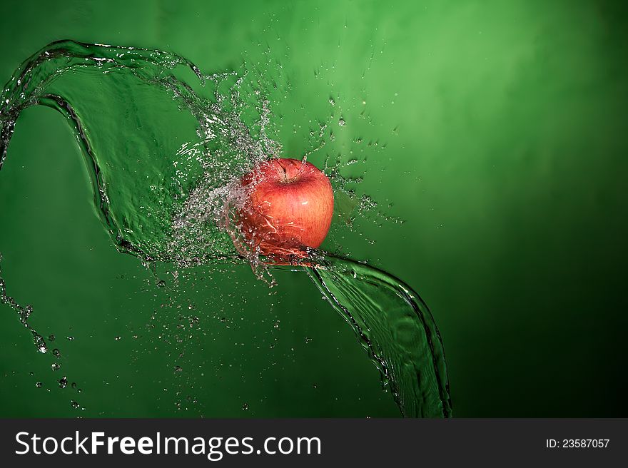 Apple splashed with water on a green background