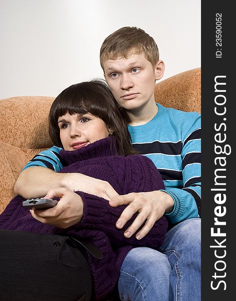 A guy and a girl watching television while lying on the couch. A guy and a girl watching television while lying on the couch