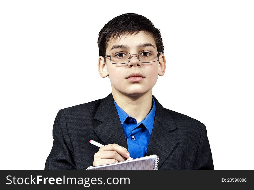 A boy with glasses writes in a notebook