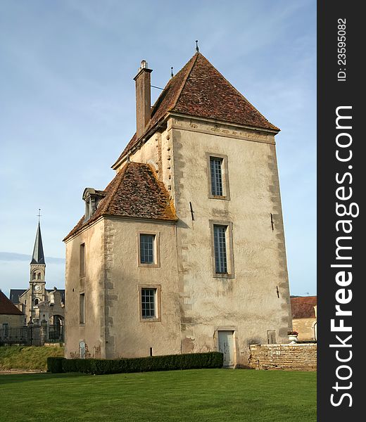 The chateau de Commarin (castle) is located in Burgundy, France. This is a secondary building on the property, with the church in the background.