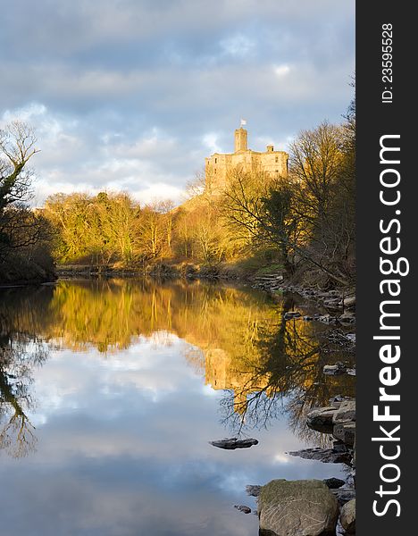 Warkworth castle lit by evening sunlight reflected in the river Coquet. Warkworth castle lit by evening sunlight reflected in the river Coquet