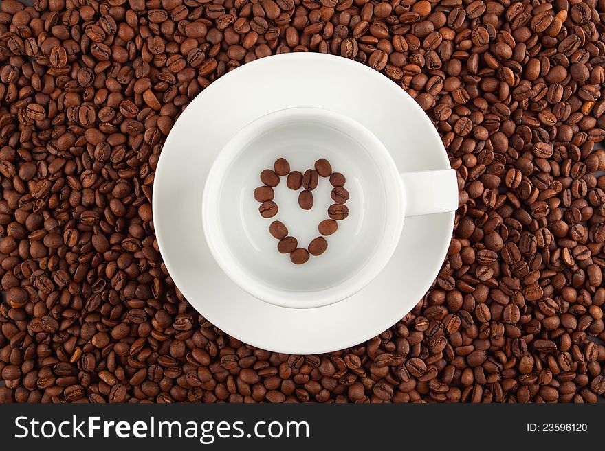 White cup placed on coffee crops with a heart symbol inside the cup. White cup placed on coffee crops with a heart symbol inside the cup