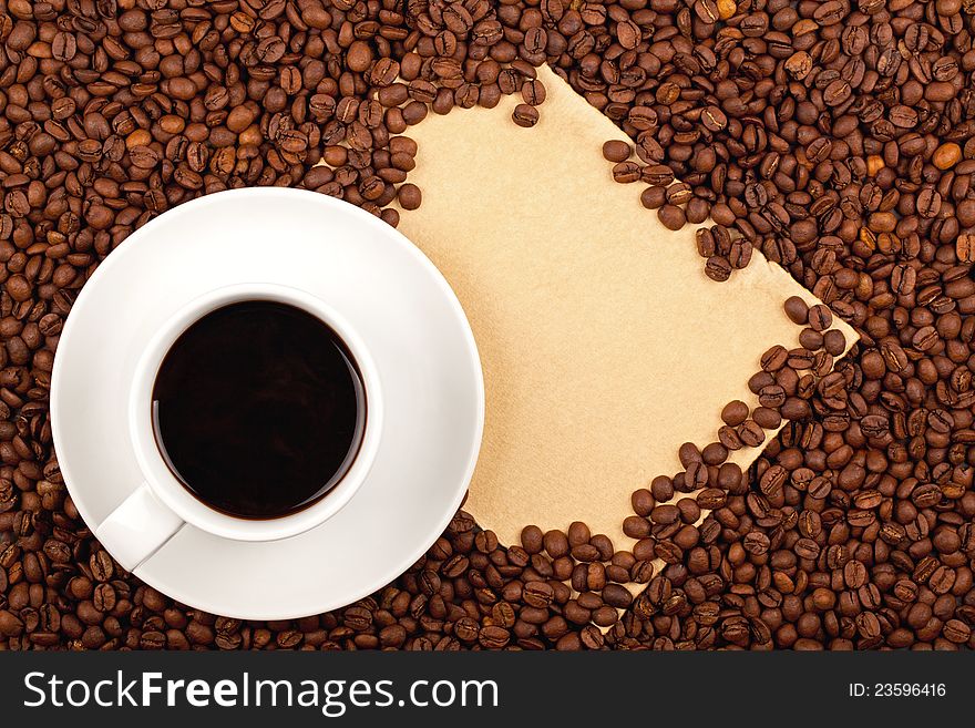 White cup full of coffee placed on coffee crops and hand-made paper for copy-space. White cup full of coffee placed on coffee crops and hand-made paper for copy-space