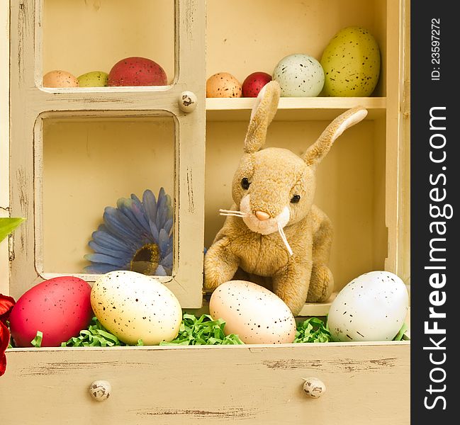 A stuffed Easter bunny in a cupboard full of speckled Easter eggs. A stuffed Easter bunny in a cupboard full of speckled Easter eggs.