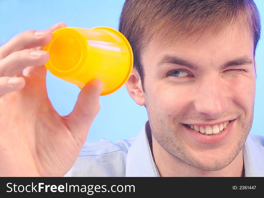 Young  man with  smile looks in an empty plastic glass