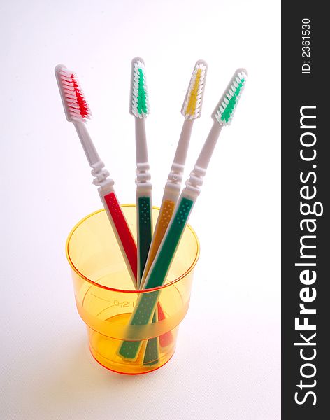 Four tooth-brushes in  plastic orange glass on  white background. Four tooth-brushes in  plastic orange glass on  white background