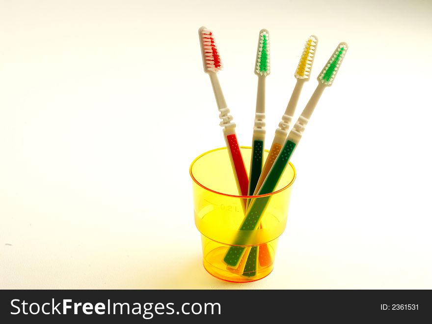 Four tooth-brushes in  plastic orange glass on  white background
