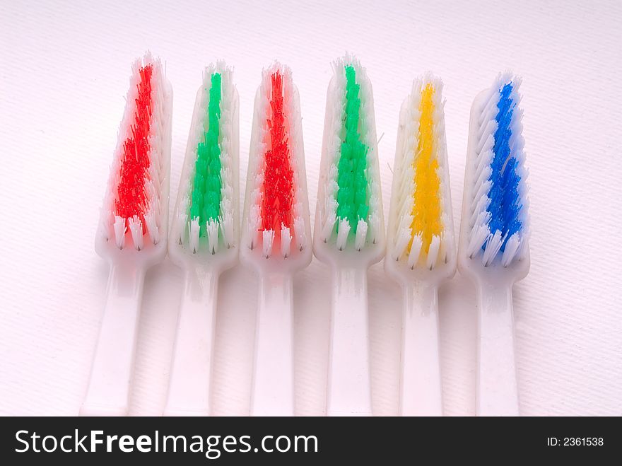 Six new tooth-brushes of different colors on  white background, close-up. Six new tooth-brushes of different colors on  white background, close-up