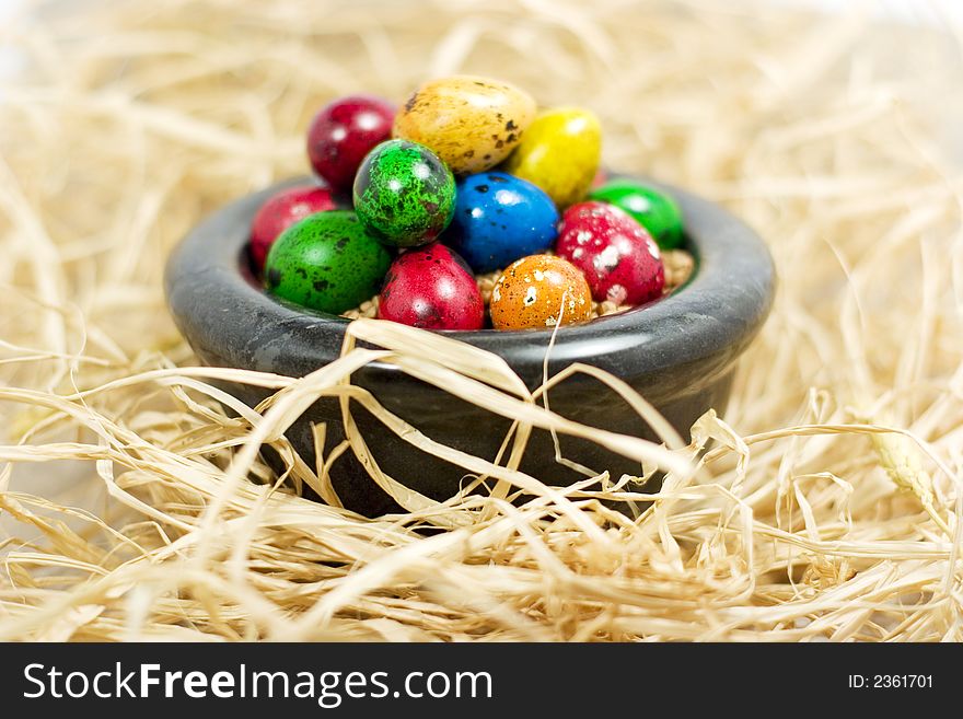 Colorful eggs in bowl in straw