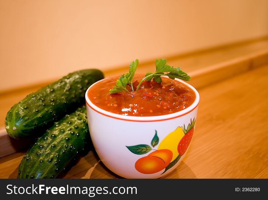 Ketchup with parsley twig and cucumbers over wooden table. Ketchup with parsley twig and cucumbers over wooden table