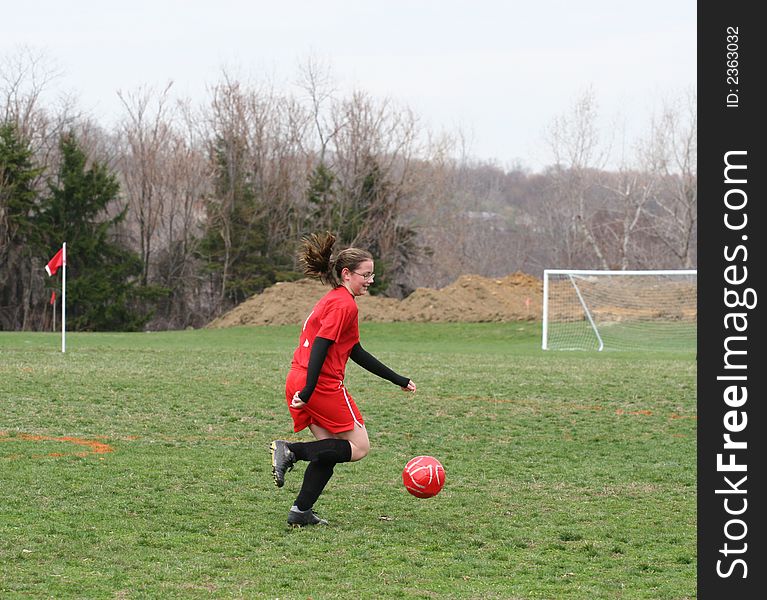 Girl chasing soccer ball down the field. Girl chasing soccer ball down the field.