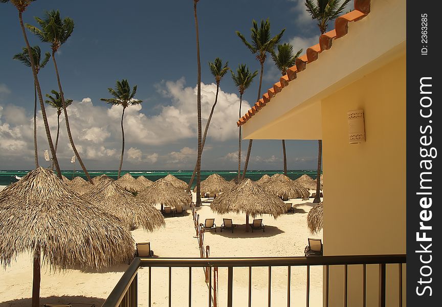 Hot sunny beach with grass sunshades shading lounge chairs. Hot sunny beach with grass sunshades shading lounge chairs.