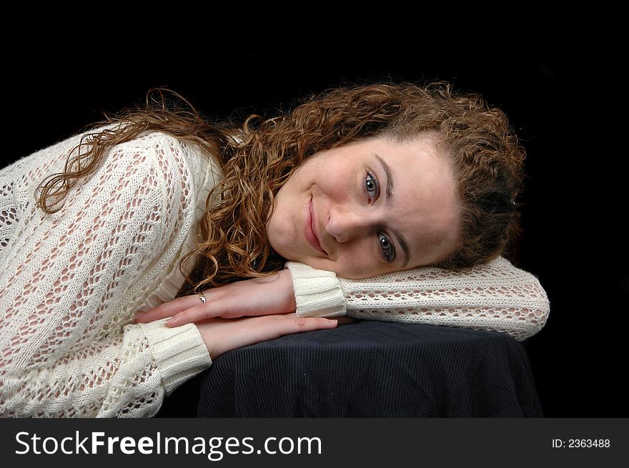 Teen girl portrait with curly hair smiling against a black background