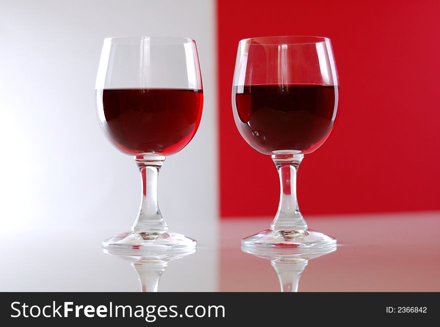 Two wine glasses over white and red background. Two wine glasses over white and red background.