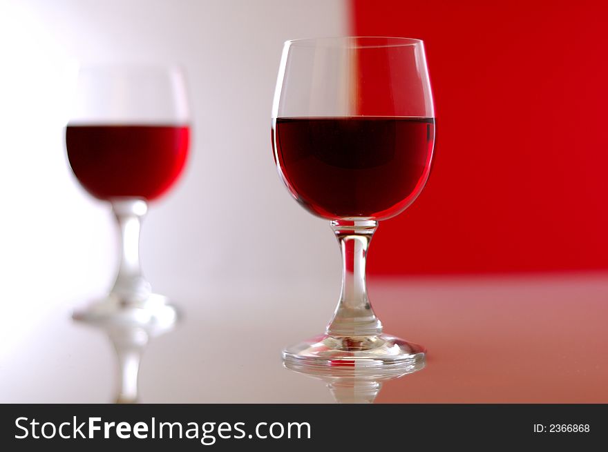 Two wine glasses over white-red background. Shallow depth of field.